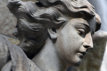 Partial view of the face of an old sandstone sculpture of an angel.