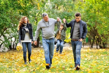 Obraz premium Happy family walking together in autumn park