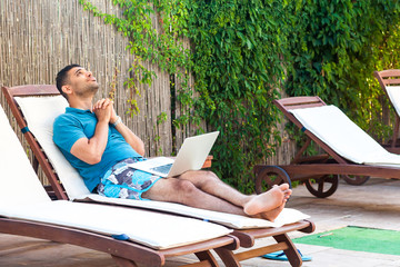 Portrait of pleading handsome bearded young adult prayer man in blue t-shirt and shorts lying on...