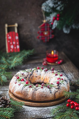 Traditional homemade christmas cake holiday dessert with cranberry and chocolate with new year tree decoration on vintage wooden table background. Rustic style.
