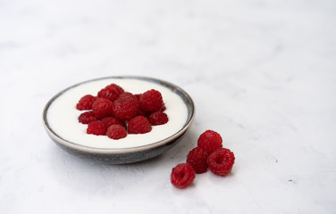 Tasty fresh raspberries yoghurt shake dessert in ceramic bowl standing on white table background.