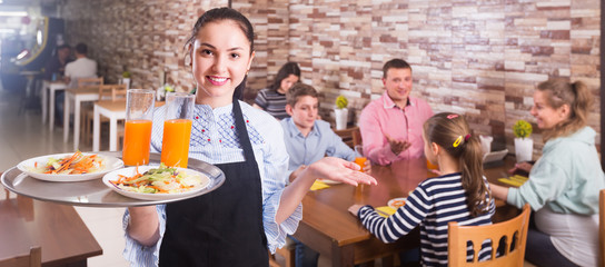 Emotional waitress holding tray with dishes meeting visitors - obrazy, fototapety, plakaty