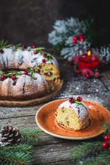 Traditional homemade christmas cake holiday dessert with cranberry and chocolate with new year tree decoration on vintage wooden table background. Rustic style.