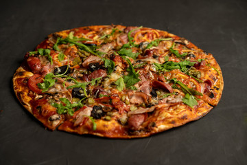 Appetizing pizza with smoked sausages bacon meat tomato cheese arugula