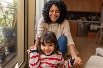 Fototapeta premium Smiling little girl and her mother sitting together at home