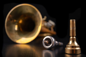 Mouthpiece and trumpet covered with patina on a dark table. Accessories for musicians ready to use.