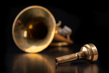 Mouthpiece and trumpet covered with patina on a dark table. Accessories for musicians ready to use.