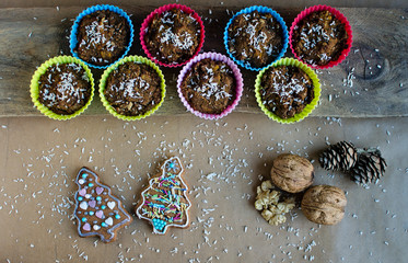 Colorful cupcakes and christmas cookies with nuts on the wooden board on the table in the kitchen. Christmas decoration. top view.