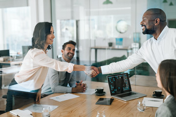 Smiling businessspeople shaking hands together during a boardroom meeting
