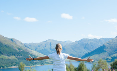 woman looking at a lake between mountains
