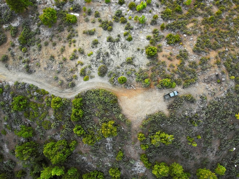 Aerial drone view looking down on rugged wilderness mountain top terrain with pickup truck
