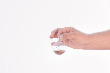 A hand holding a small ball of transparent plastic, filled with small coloured stars on a white background. Space to write.