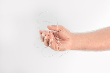 Hand entangled by a cable with many small lights on a white background and space to write.