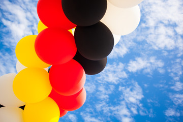 Balloons - Colors of the German National Flag (black, red, yellow)  - outdoors against blue Sky...