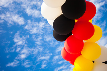 Balloons - Colors of the German National Flag (black, red, yellow)  - outdoors against blue Sky...