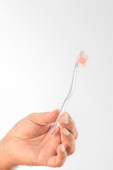 A hand holding a transparent plastic brush on a white background.