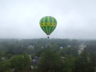 Green hot air balloon floating in fog