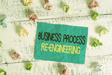 Word writing text Business Process Re Engineering. Business photo showcasing the analysis and design of workflows Crumpled colored rectangle square shaped paper reminder white wood desk