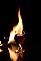 red drink with fire behind and reflection on black background