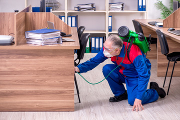 Old professional contractor doing pest control in the office