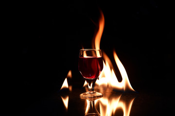 red drink with fire behind and reflection on black background