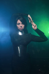 Fototapeta premium futuristic fashion model wearing black and silver clothes and standing in the colorful blue and green smoke
