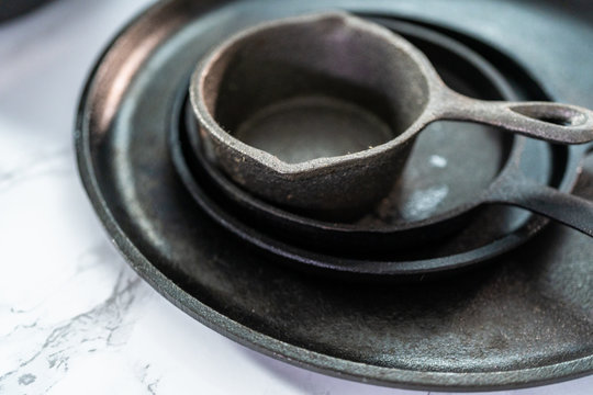 Flat lay. Variety of cast iron frying pans on a marble background.
