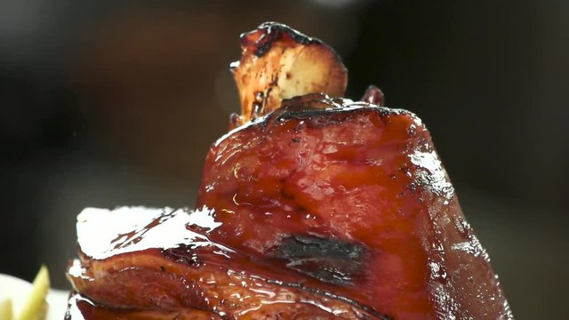 CLose up top of burining lamb shank. Shank of lamb with flavor sauce and spices, slow-motion, macro view.