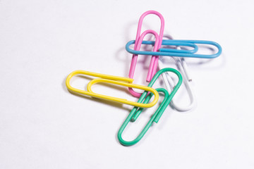 Several colored metal clips lying on a white matte surface