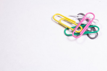 Several colored metal clips lying on a white matte surface