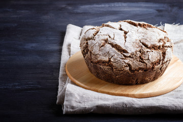 Yeast free homemade bread with whole rye and wheat grains on black wooden background.