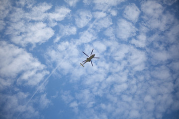 A helicopter flies in the sky. Propeller transport on a background of blue sky. Bottom view of the movement of the aircraft.