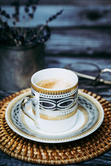 Tasse de café en porcelaine blanche et dorée sur une table en bois vintage