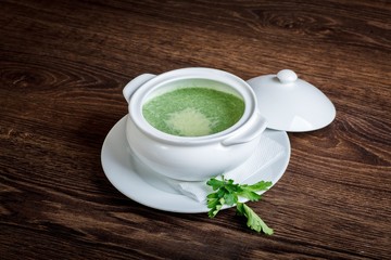 Vegetarian spinach soup in white bowl on a dark table