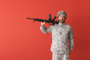 Soldier with assault rifle on color background