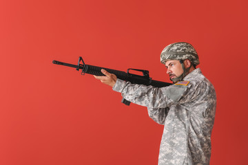 Soldier in camouflage taking aim on color background