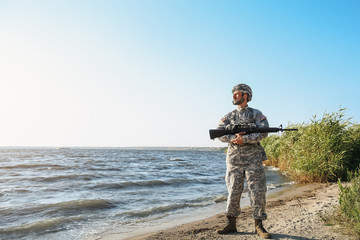 Soldier with assault rifle near river