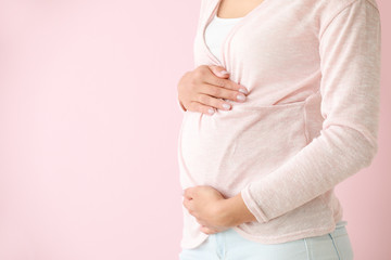 Young pregnant woman on color background