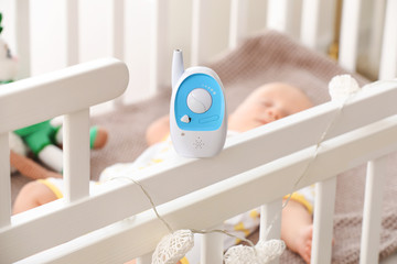 Modern baby monitor on crib of sleeping infant