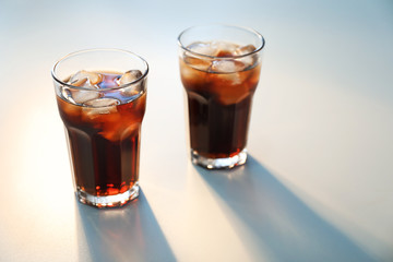 Glasses of cold cola on light background