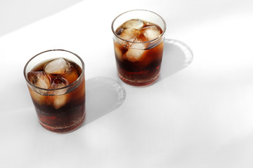 Glasses of cold cola on light background