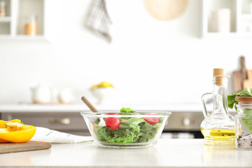 Fototapeta na wymiar Bowl with tasty salad on kitchen table