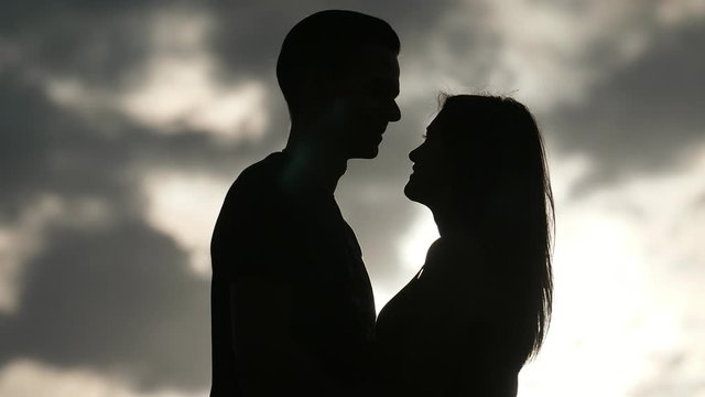 Happy boy hugging, smiling and kissing his lovely girlfriend at sunset in slo-mo 