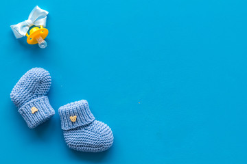 Booties for newborn boy with dummy on blue background top view mock up - obrazy, fototapety, plakaty