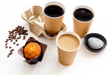 Coffee to take away in paper cups, beans with muffin on white table background