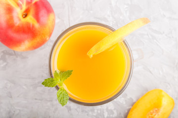 Glass of peach juice on a gray concrete background. Top view