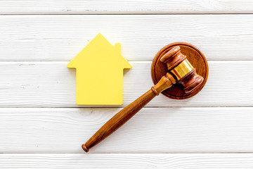 Inheritance of the house concept with figure and gavel on white wooden background top view