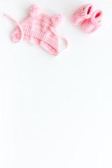 Knitted pink footwear and hat for baby on white background top view mockup