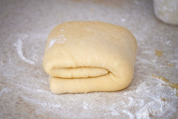 A piece of butter dough for making homemade pastries. Closeup dough for roll with poppy seeds on the table. The process of making homemade sweet pastries for tea or coffee.