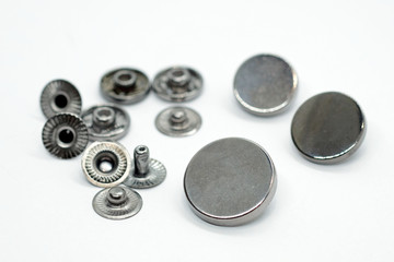 Metal button for clothes, nickel color. Sewing accessories for outerwear production. Components of the press-stud with a flat top on a white background close-up.